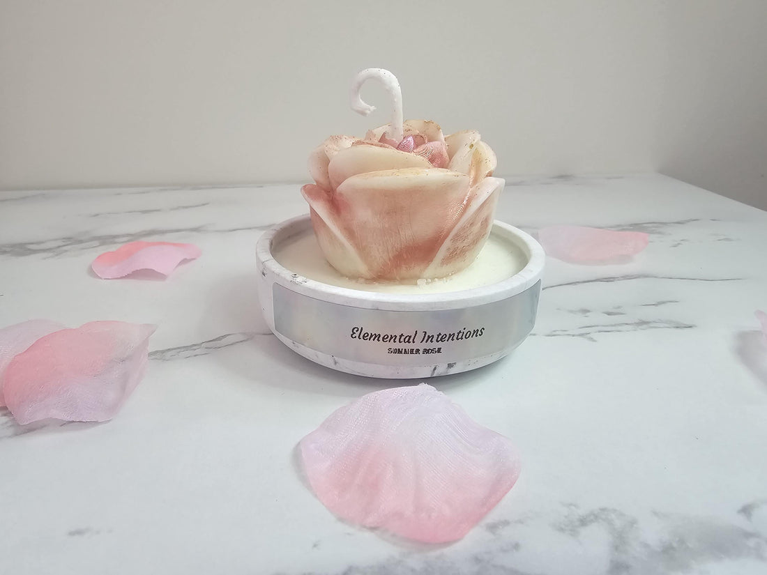 A grey resin cement candle holder with a rose shaped pink and white aromatherapy candle surrounded by flower petals