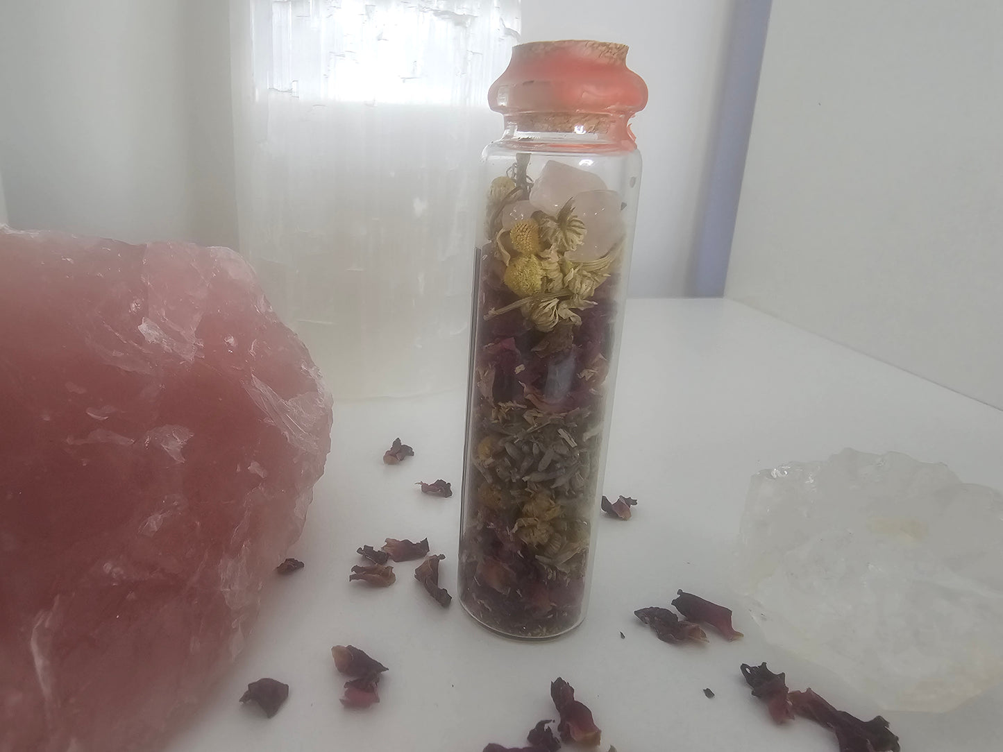 Small glass spell jar sealed with red wax and filled with herbs and crystals.