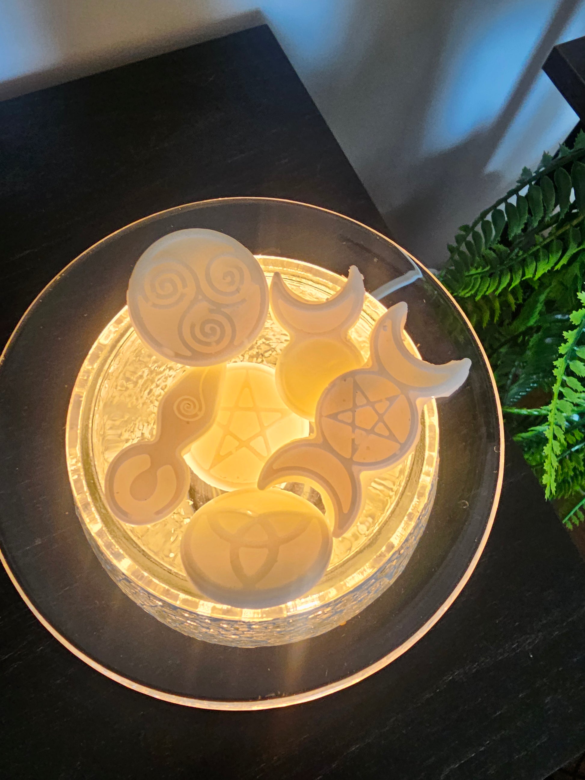Scented soy wax melts with witchy designs and shapes on a lit wax burner