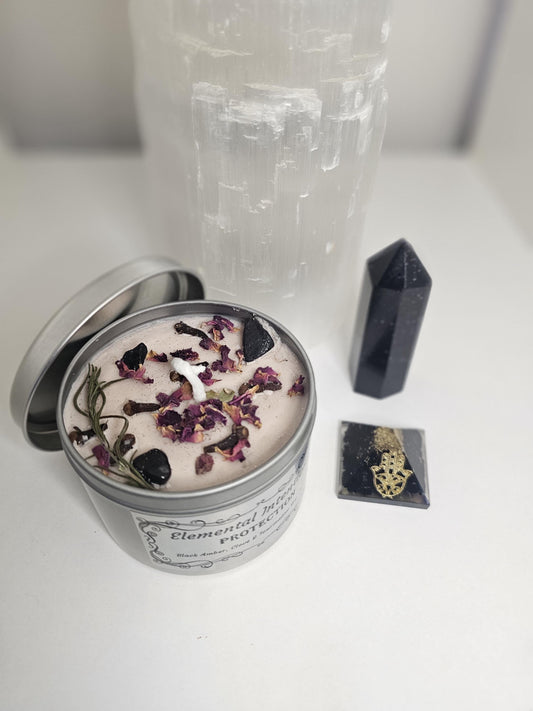 A silver container candle with nude coloured soy candle wax and cotton wicks, topped with black tourmaline, rose petals and rosemary leaves.